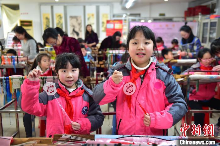 圖為小學生展示繡制好的2022年北京冬奧會吉祥物“冰墩墩”形象。　喻云亮 攝