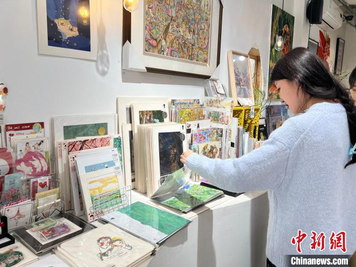 圖為藝術(shù)品商店內(nèi)，顧客挑選插畫作品?！＄婌?攝