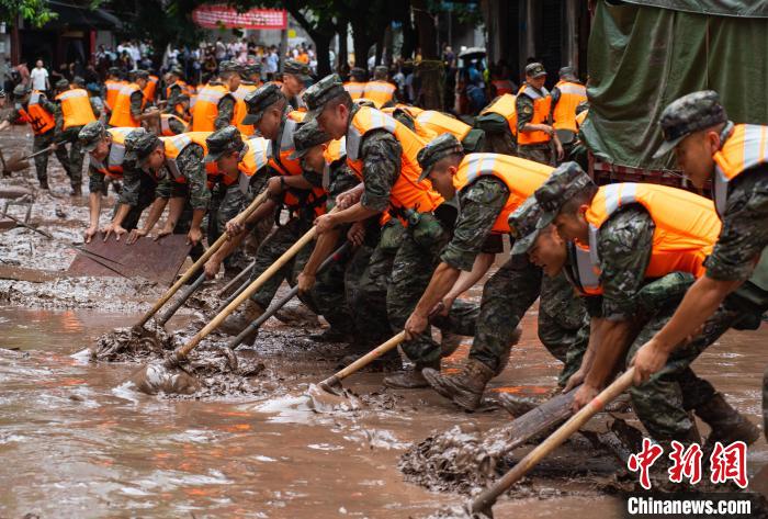 7月4日，萬(wàn)州區(qū)五橋街道，武警官兵清理街道上的淤泥。　冉孟軍 攝