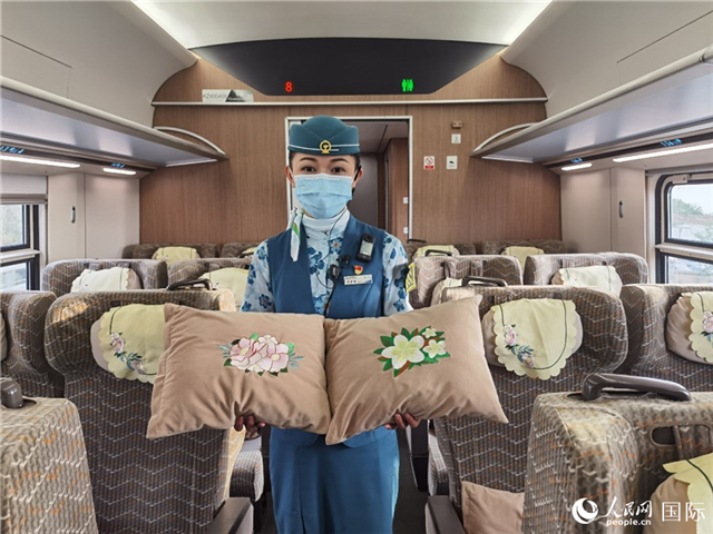 趙瑩靜展示中老鐵路國際旅客列車里帶有中國牡丹花和老撾占巴花刺繡圖案的靠墊。人民網記者 杜明明攝