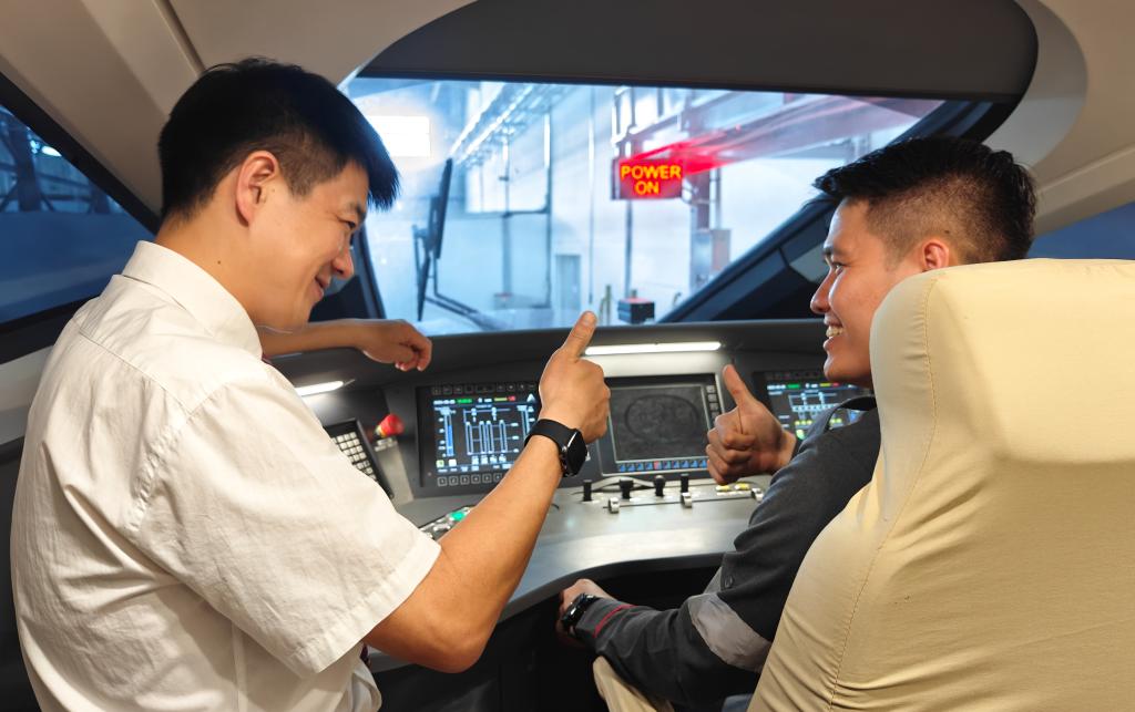 8月25日，在印度尼西亞萬隆的雅萬高鐵德卡魯爾動車所內，中國師傅穆振（左）在向印尼火車司機塞蒂亞萬講解動車組出庫前的上電作業。