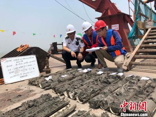 圖為勘察設(shè)計人員與海事局工作人員查看巖芯情況。　魏震 攝
