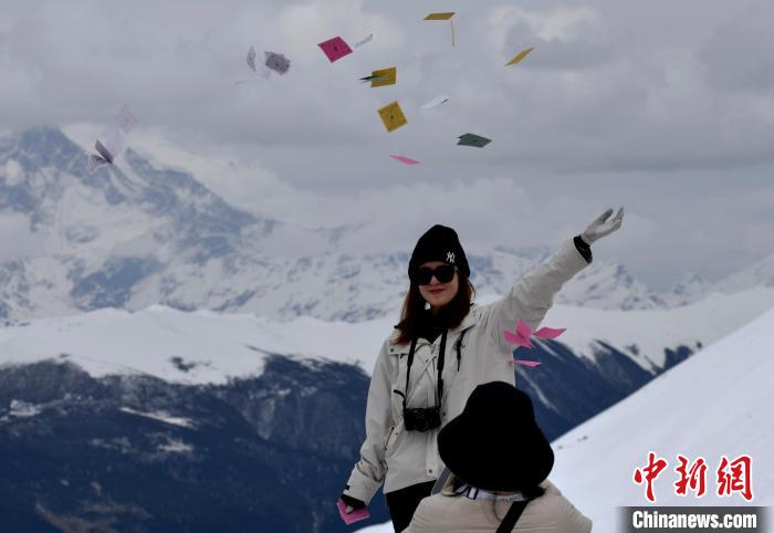 圖為5月14日，游客在西藏林芝色季拉山觀景臺拋灑“隆達”(風馬旗，藏族民眾的一種祈福方式)。　李林 攝