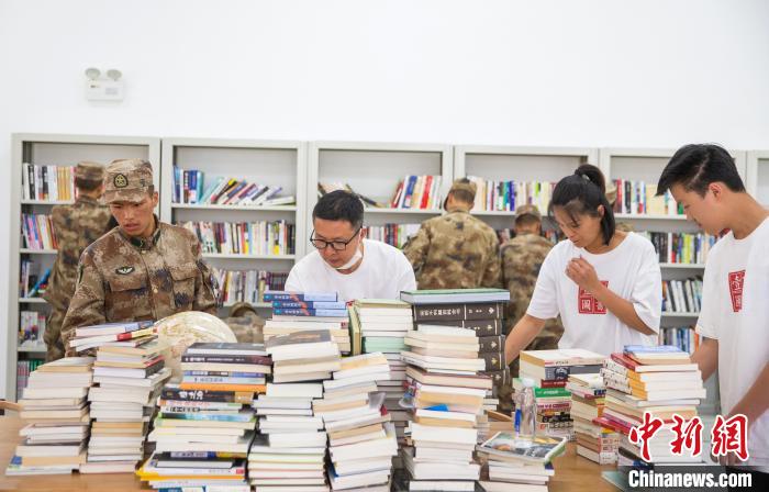圖為志愿者們和邊防戰士整理圖書。　劉曉東 攝