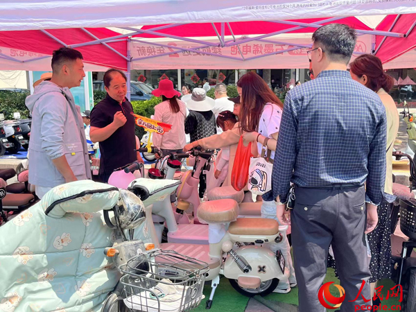 某電動自行車品牌工作人員向消費者介紹以舊換新相關(guān)情況。人民網(wǎng)記者 杜燕飛攝