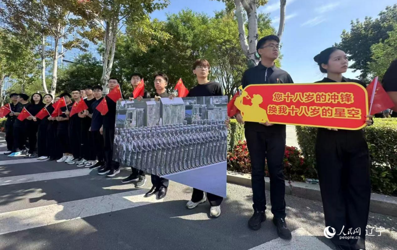 沈陽市人民廣場(chǎng)上，大學(xué)生們手持閱兵的圖片，告慰英烈。人民網(wǎng)記者 周頌雪攝