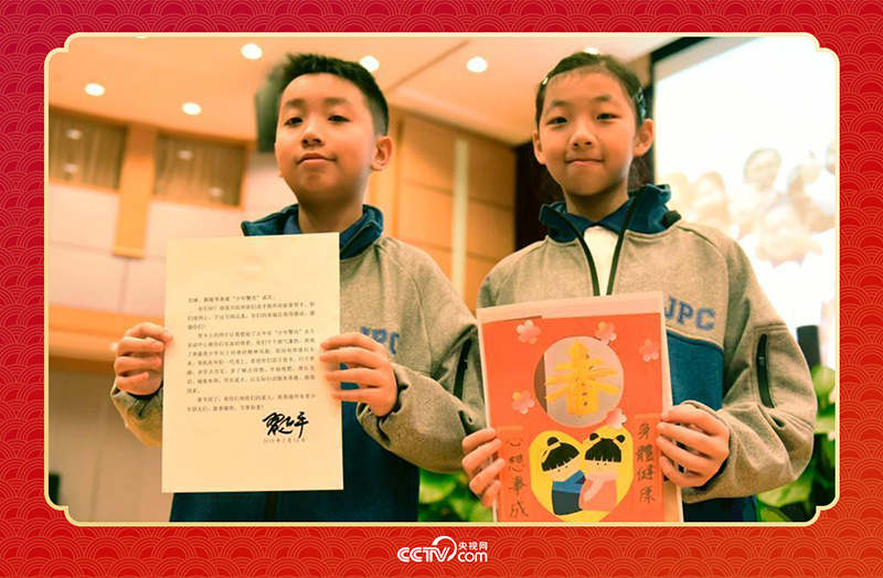 圖為香港“少年警訊”成員郭宏晞（左）展示習主席回信、羅顥凝（右）展示送給習主席的賀卡并合影。
